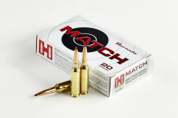 A box of Hornady Match rifle cartridges with two bullets in front of it on a white background.