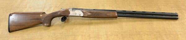 Overhead view of a wooden and metal over-under shotgun on a textured background.