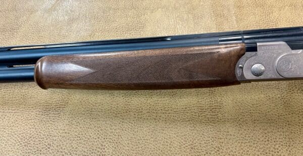 Double-barrel shotgun with wooden stock and intricate engravings on metal.