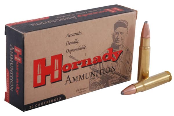 A box of Hornady ammunition with one cartridge standing and one lying down beside it.