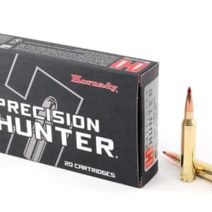 A box of Hornady Precision Hunter cartridges with two rounds beside it.