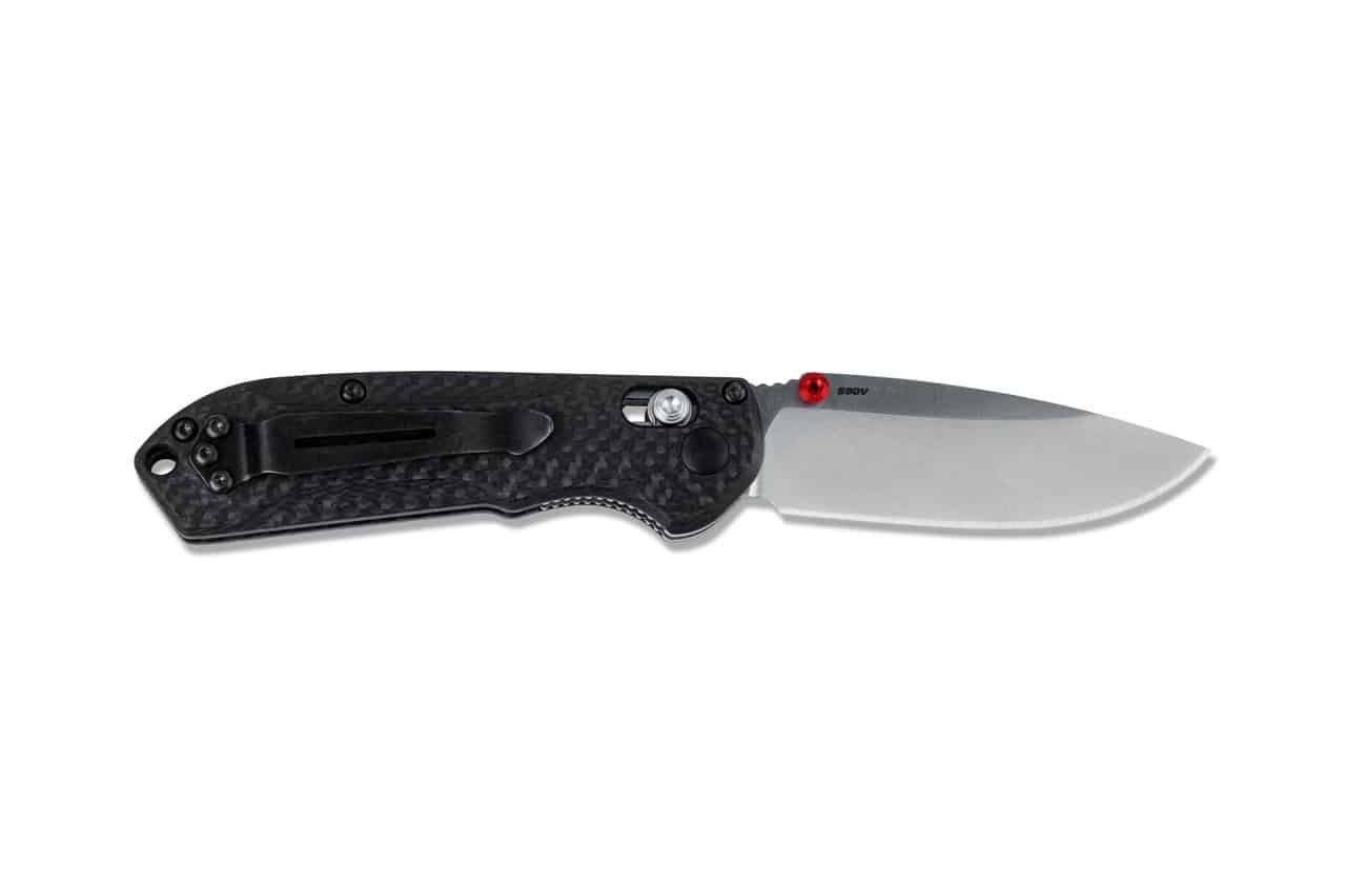 Foldable pocket knife with black carbon fiber handle, a silver blade, and a black pocket clip, laying on a white background.