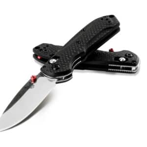 BENCHMADE MINI-FREEK - Two black and silver folding knives with carbon fiber handles, one open and one closed, isolated on white. The open knife is in the foreground with the blade extended, showing a silver steel blade with the Benchmade butterfly logo, and red accent pins. The closed knife rests behind, also showing red accent pins.