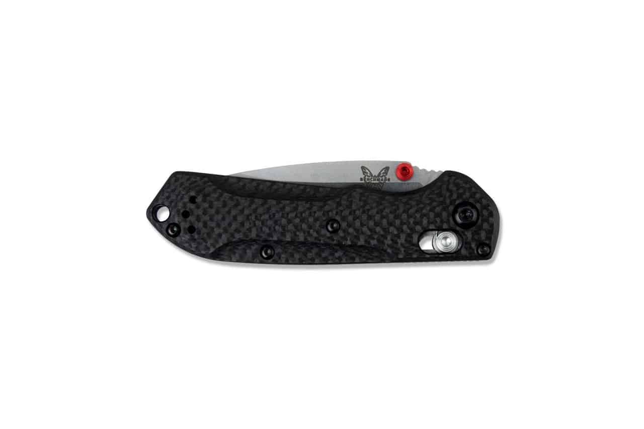 A Benchmade folding knife with a carbon fiber handle, silver blade, red thumb stud, and Benchmade butterfly logo.