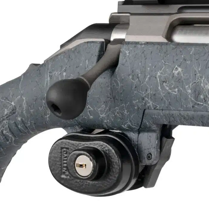 Close-up of a rifle's bolt handle alongside a secured locking mechanism on a textured gray stock.