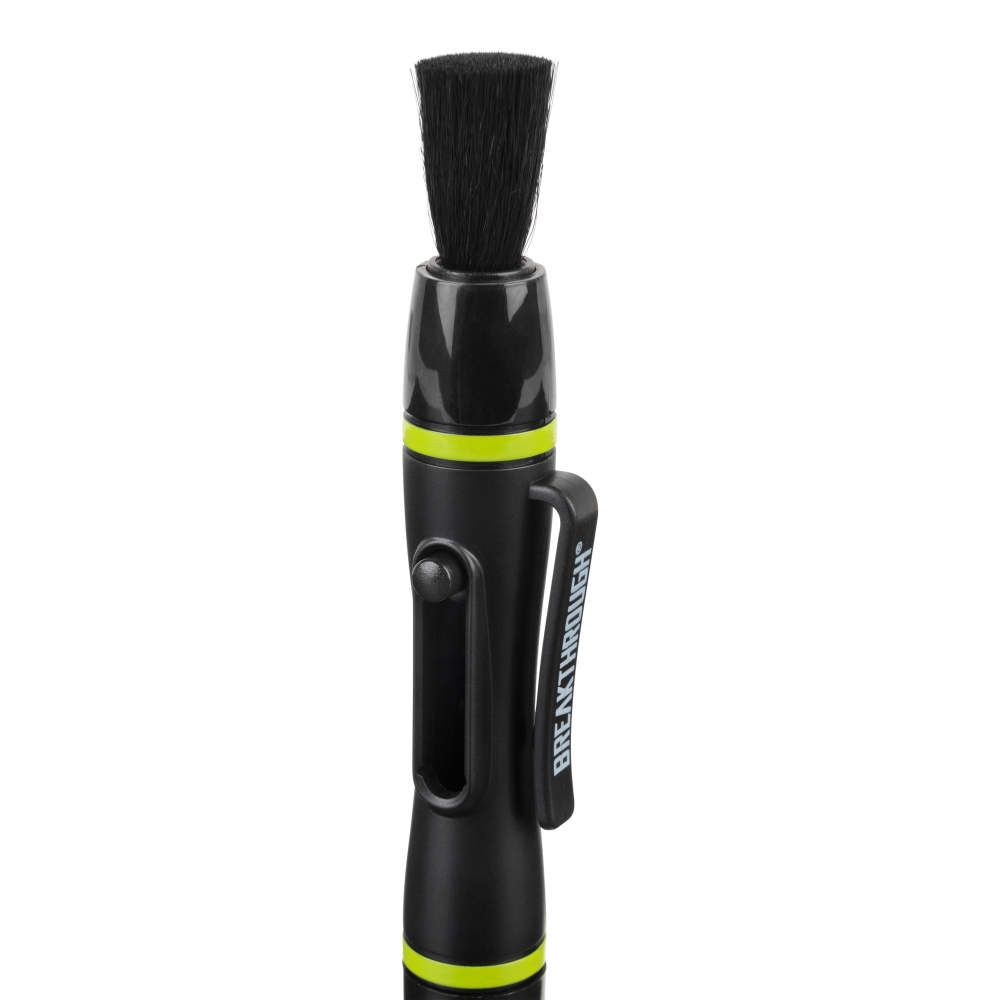 Black lens cleaning brush with a black brush head, a black handle with a green accent, and the word "BREAKTHROUGH" in white on the handle.