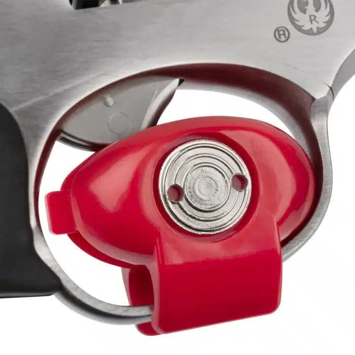 Close-up of a firearm's trigger mechanism showing a red safety lock, designed to prevent accidental discharge.