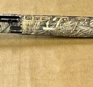 Camo-patterned shotgun with price tag on brown background.