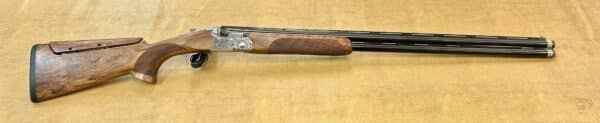 A double-barreled shotgun with intricate engravings on the metal and wooden stock.