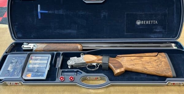 An ornate Beretta shotgun disassembled in its case with accessories.