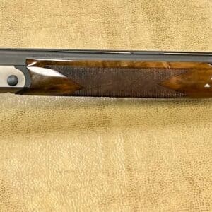 A shotgun with a wooden stock and double barrels on a textured background.