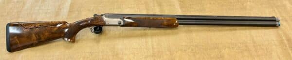 A shotgun with a wooden stock and double barrels on a textured background.