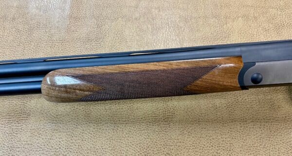 Close-up of a shotgun's wooden stock and barrels on textured background.