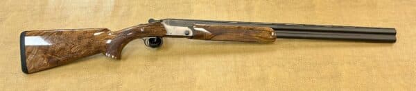 Side view of an over-under shotgun with wooden stock on a textured background.