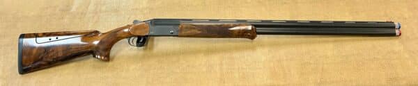 Over-under double-barreled shotgun with a wooden stock and detailed metalwork on a textured background.