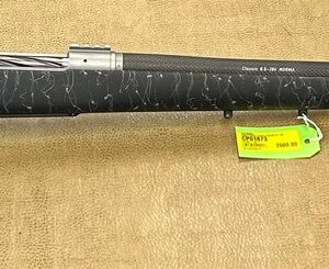 A black rifle with detailed white engraving and with a price tag on a beige background.