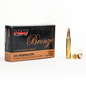 A box of PMC Bronze .223 Remington rifle cartridges next to a full bullet and casings.