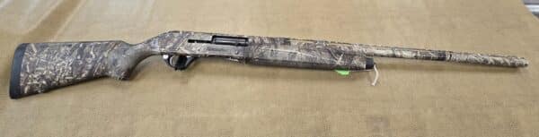 Camo-patterned Remington shotgun on a textured beige background.