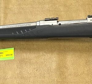 Silver and black rifle with price tag on a brown background.