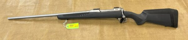 Silver and black rifle with price tag on a brown background.