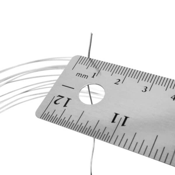 A close-up of a metal ruler measuring a thin wire, with several other wires lying alongside it on a white surface.